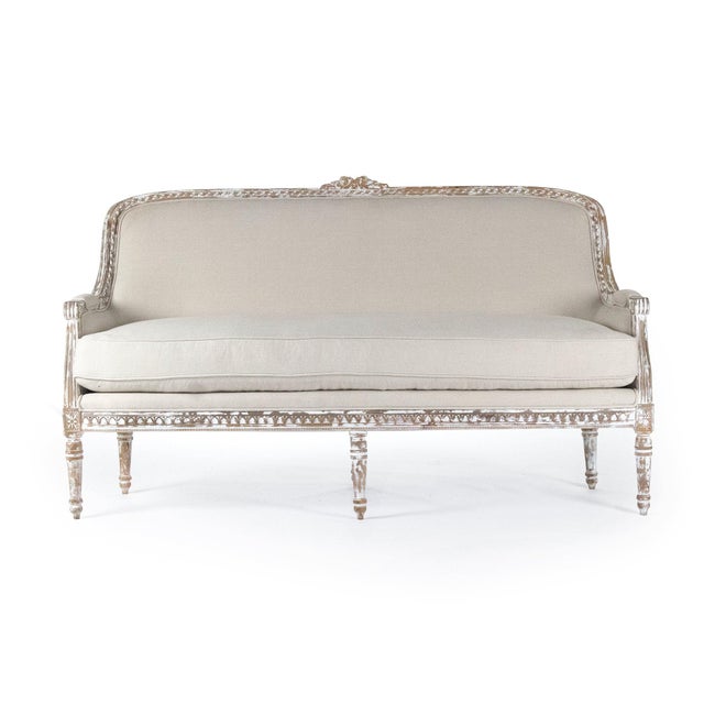 The Yvon Bench from Zentique is a French Louis XVI canapé-style bench with a carved arched back, scrolled arms, off-white...