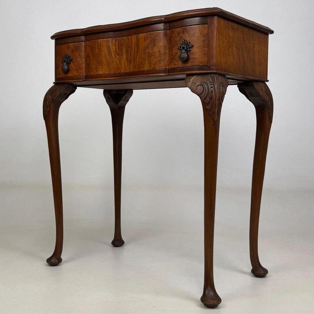 A graceful and beautifully crafted early 20th-century English Edwardian side table, constructed in richly figured walnut...