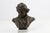 The bust is crafted with a rich bronze-toned finish and comes securely mounted on a solid, polished white/gray veined...