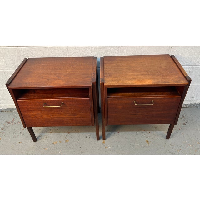 Elegant pair of mid-century modern walnut nightstands designed by Jens Risom, showcasing the designer’s signature balance...
