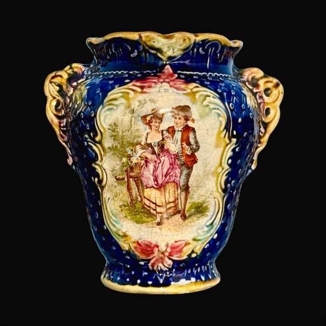 This antique Victorian Majolica vase features a striking cobalt blue glaze, dual ornate handles, and a hand-painted...