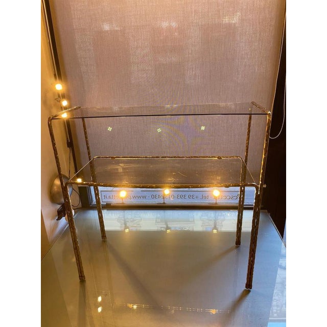 Console with a hammered brass frame and two smoked glass shelves in different sizes, arranged to create an elegant bombe...