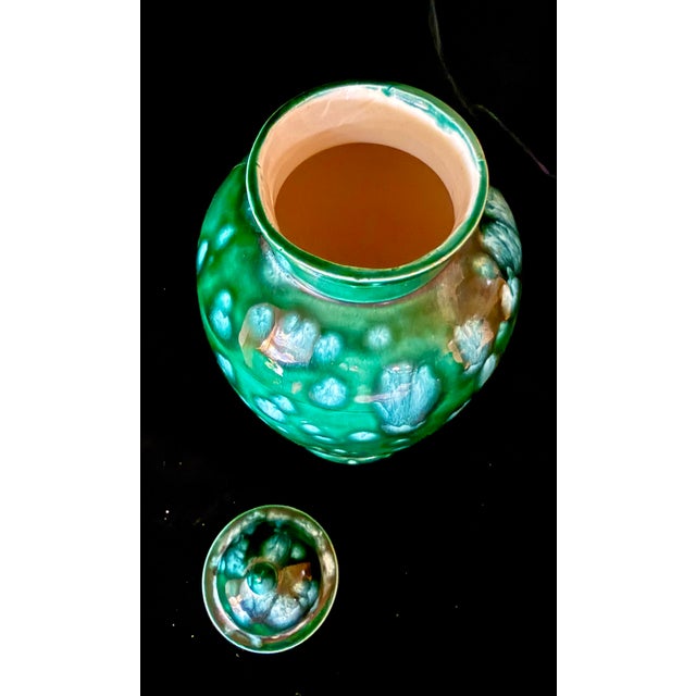 This elegant ceramic jar features a vibrant green glaze with a characteristic motted or ‘speckled’ pattern, topped with a...