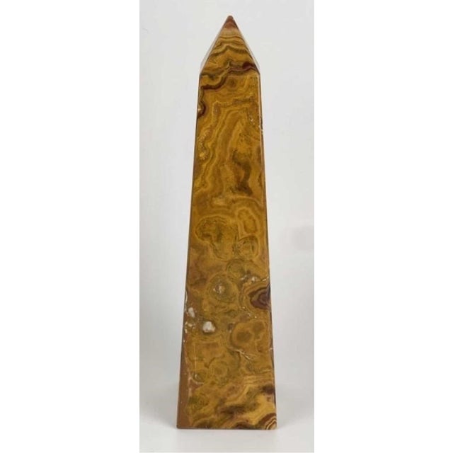 A hand-carved banded onyx obelisk, polished to a lustrous shine. Warm layers of brown, amber, and butterscotch ribbon...