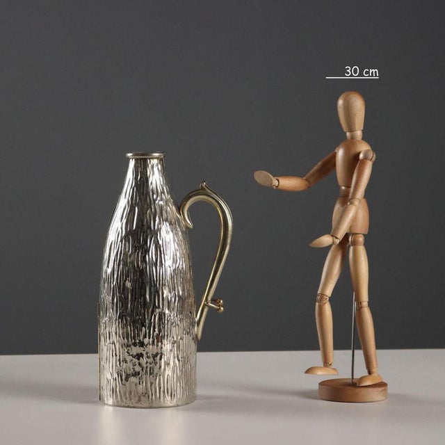 Embossed silver-plated metal bottle holder. Unique click-clack closure. Parchment-lined interior. Serial number engraved...