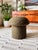 A handmade mushroom shaped ottoman, upholstered in a dotted wool blend fabric. "Sequoia" fabric is in the olive green...