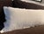 Discontinued CB2 Bettie oversized lumbar pillow in warm white velvet. The elongated silhouette features tonal fringe along...