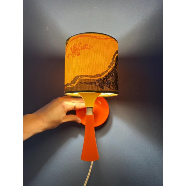 Orange space age textile wall lamp. The orange sconce made out of synthetic material, it carries a textile shade. The lamp...