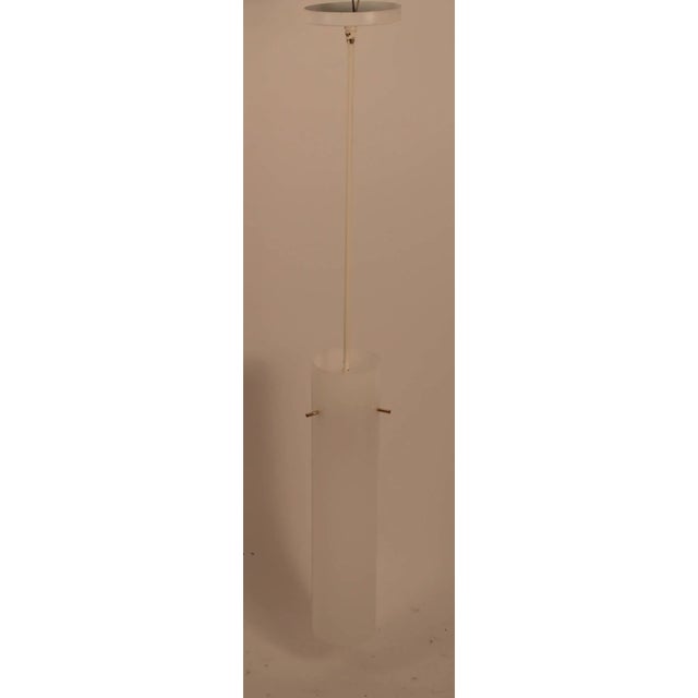 Pair of tubular plastic hanging fixtures. Each fixture has three brass elements which support the white shade, which hangs...