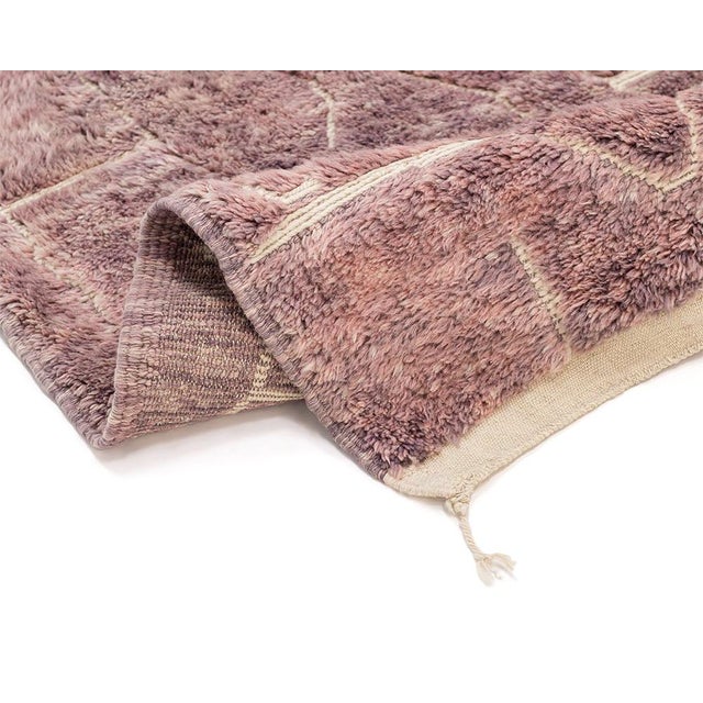 A soft blush field, alive with a whisper of overlapping diamonds. This hand-knotted wool rug builds its quiet richness...