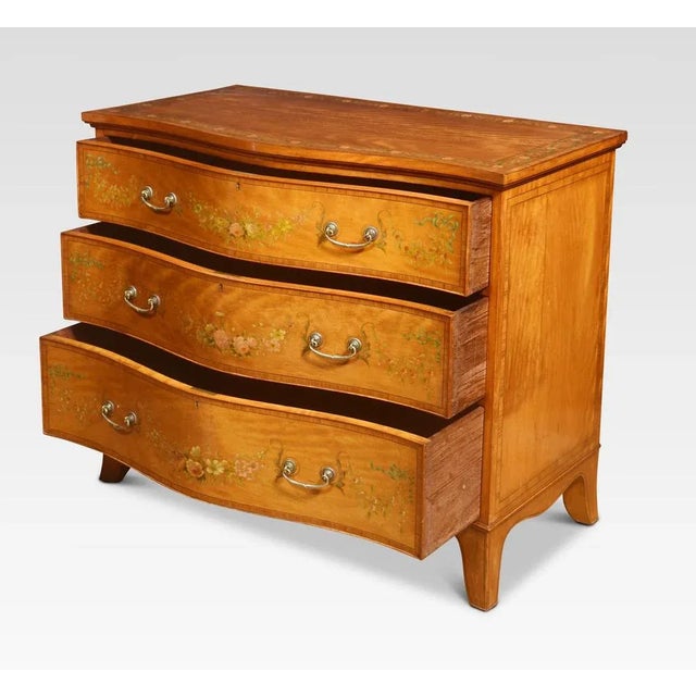 Satinwood chest of drawers, the large rectangular serpentine top having floral painted banding above three long graduated...
