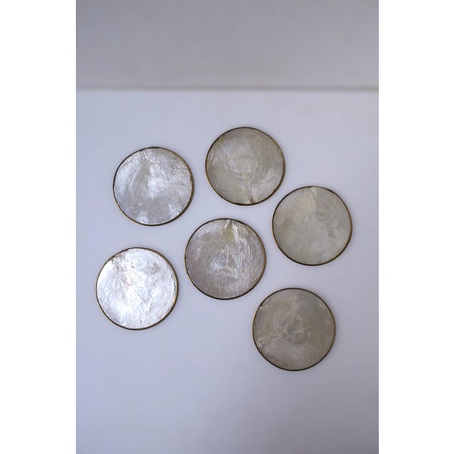 A set of six (6) white seashell coasters with gold gilt edge and cork bottom, circa mid-late 20th century. Set appears to...