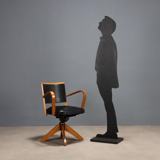 Swivel chair with wooden frame, seat and back in black leatherette. This piece is attributed to the mentioned...