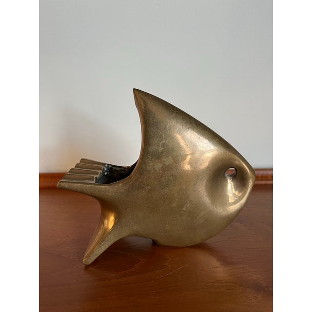 Vintage mid century brass sculptural fish ashtray featuring a bold modernist silhouette and rich golden patina. A striking...