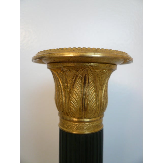 This handsome pair of bronze candlesticks feature Classical motifs including acanthus leaves and reeded tapering shafts.
