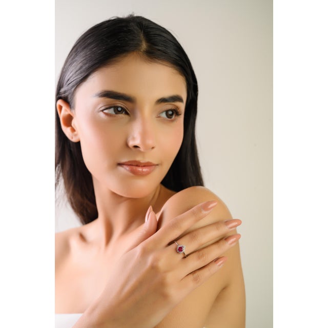 This handmade halo engagement ring showcases a one vibrant natural Mozambique pear-cut ruby totaling 0.65 carats set in...