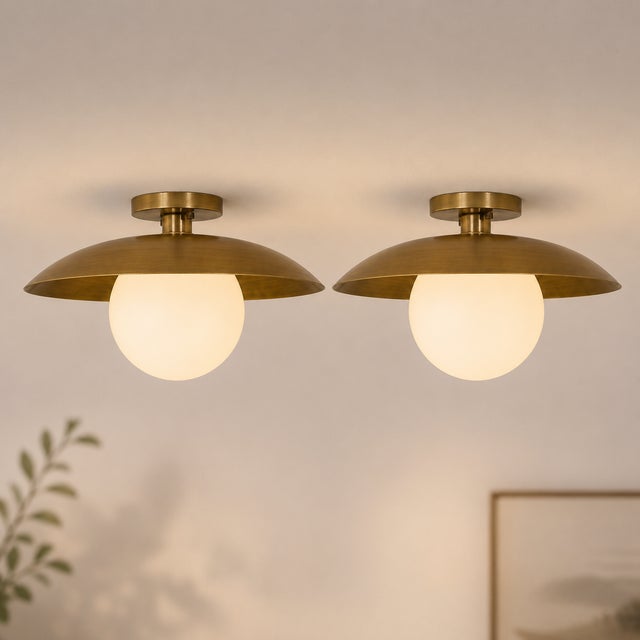 Crafted from solid brass and paired with a softly diffused opal glass globe, this flush mount ceiling light offers a...