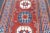 This SW Caucasian long rug, not a Kuba, displays a madder red field with four stacked octagons alternating in medium blue...