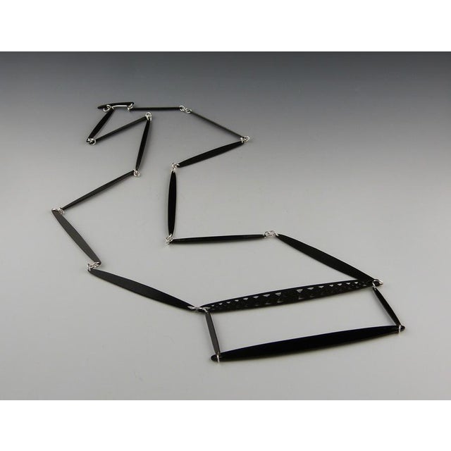 A series of graphic 2-dimensional teardrop chain-link forms, connect symmetrically to two larger contrasting horizontal...