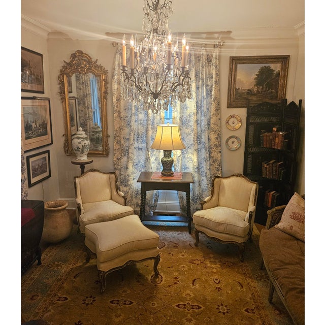 A pair of French Louis XV-style winged bergère chairs, complete with a matching ottoman, exudes elegance and...