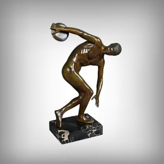 A bronze sculpture with a brown patina depicting the famous Discobolus, attributed to the Greek sculptor Myron, captures...