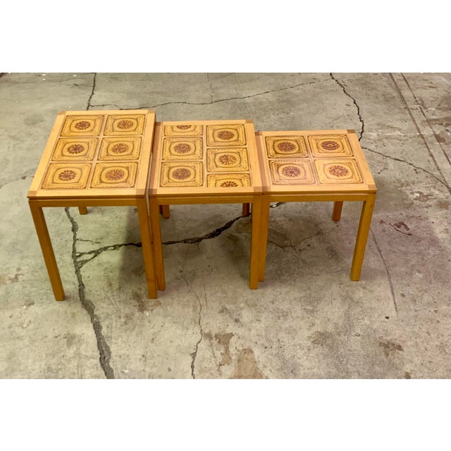 Set of three Danish modern nesting tables by Willy Ryomgard Mobelfabriken. The tables have teak frames, with ceramic tile...