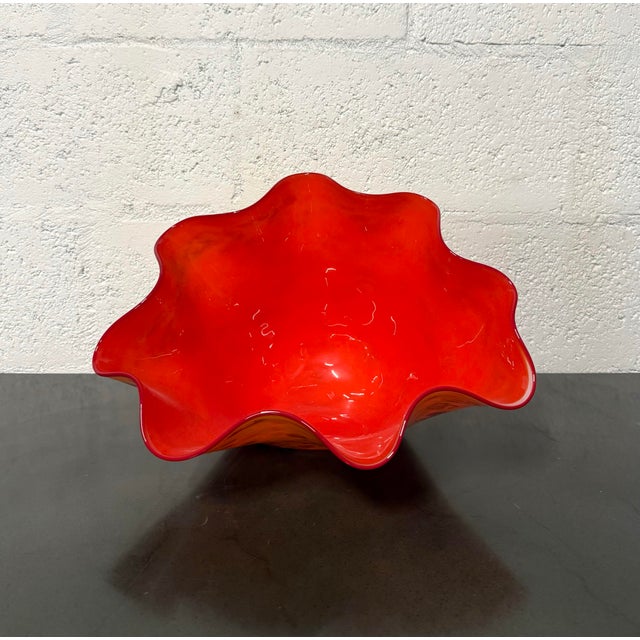 Sculptural hand-blown art glass bowl featuring a vivid red-orange interior and golden yellow exterior mottled with amber,...