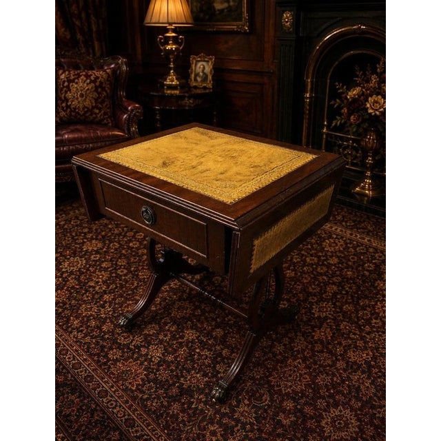 An elegant Regency-style mahogany drop-leaf side table, combining classical proportions with a beautifully aged gilt-...