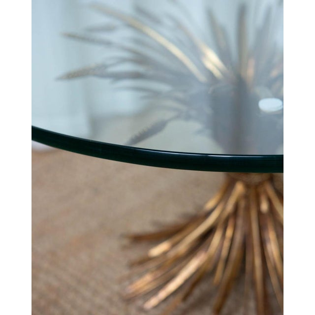 A striking 1970s bronze sheaf of wheat coffee table, featuring a sculptural bundle of wheat stalks supporting a glass top....