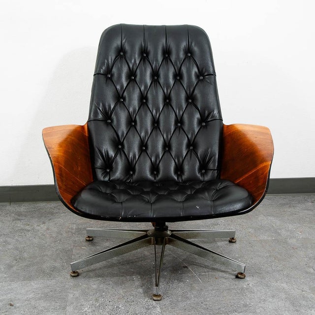 This molded ply lounge chair by George Mulhauser features stylish wing-like arms, tufted vinyl, and metal swivel base. The...