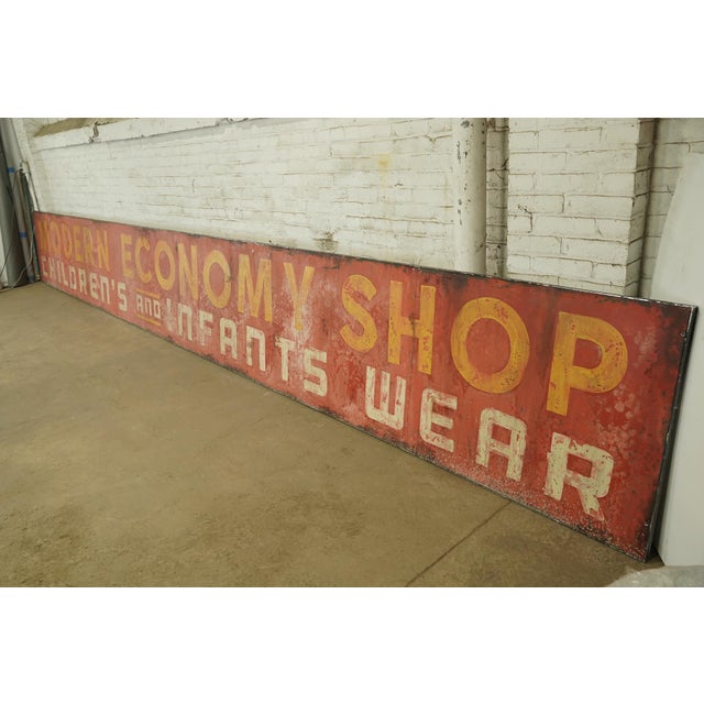 Reclaimed movie set sign made of aluminum in yellow, red, and white colors. The sign reads "Modern Economy Shop,...
