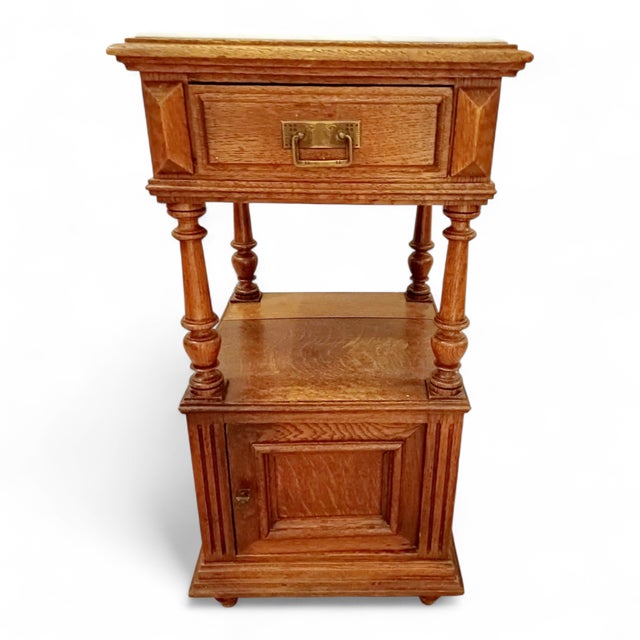 An exceptional French antique nightstand dating from the 1890s, crafted in richly grained solid oak and crowned with an...