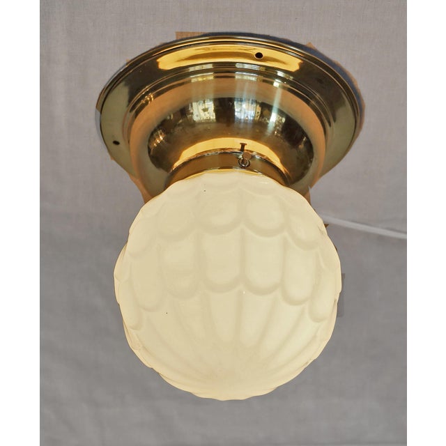 Art Nouveau ceiling lamp, circa 1915. Dish-shaped brass body. Original ivory-colored glass shade. The lamp has been...