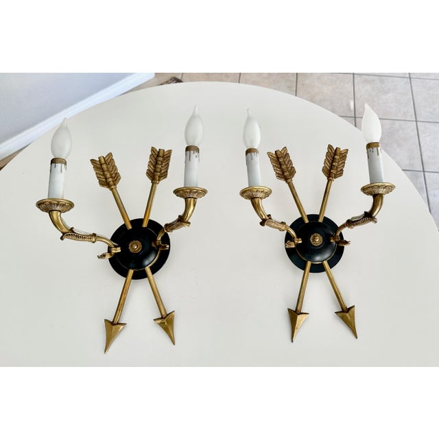 Pair of French Empire style brass and ebonized 2 light wall sconces with arrow and swan motif. A later backplate has been...
