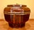 An antique Chinese wooden lidded storage vessel in a deep reddish-brown lacquer and decorated with faded black and gilt...