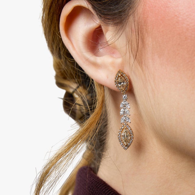 A dramatic and elegant pair of modern drop earrings showcasing the striking beauty of marquise cut diamonds. Four marquise...