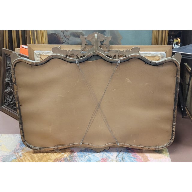 Fine antique 1920s mantel mirror. Carved in the rococo style with drapes, scrolls, flowers, tassels and swags. Measuring...