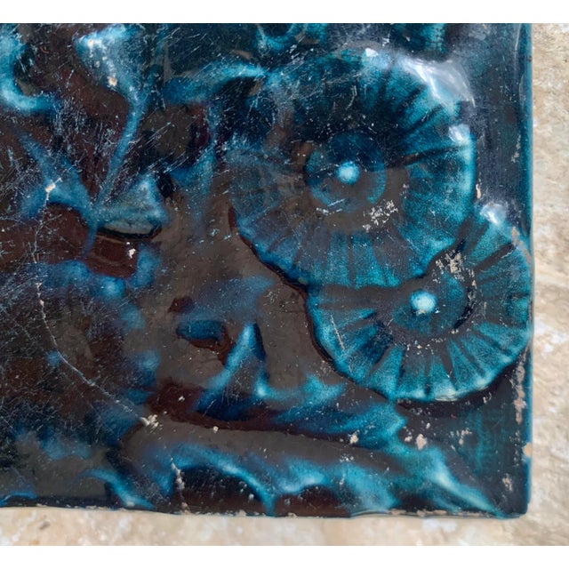 Early 20th century 'Arts and Crafts' style botanical monochromatic relief glazed ceramic tile in a deep inky blue. One-of-...