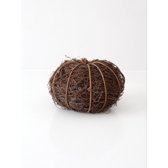Sculptural vintage grapevine pumpkin crafted from tightly bundled natural vines, with thicker strands defining its rounded...