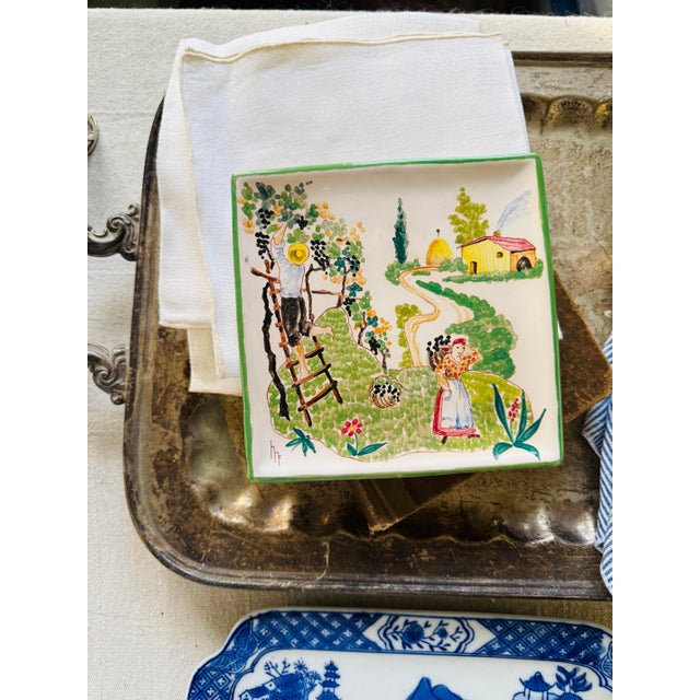 A richly detailed hand-painted Italian ceramic wall plate depicting an autumn countryside harvest scene, with figures...