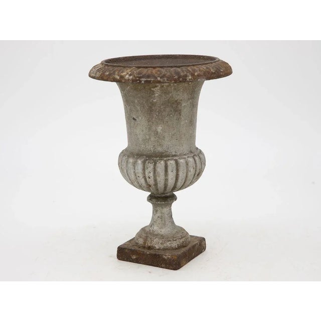 A Mid 20th century gray slightly metallic painted cast iron urn. This urn features an egg and dart pattern on the top rim...