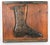 A vintage Victorian cobbler’s trade sign depicting a carved wooden relief of a high-buttoned boot mounted on a rustic pine...