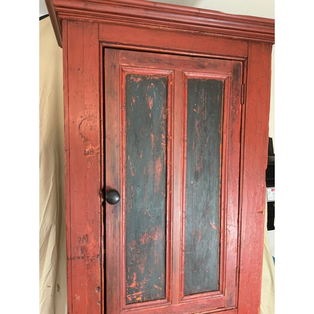 A nice 19th century New England primitive Pine two door Cupboard in old red paint over the original Salmon color. Through...