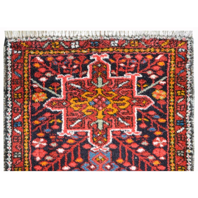 A vintage petite Persian Karadja rug with three stylized floral medallions woven in red, orange, white, and light indigo,...