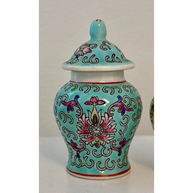 Vibrant trio of miniature lidded porcelain jars from Jingdezhen, each hand‑painted in rich turquoise, yellow, and...