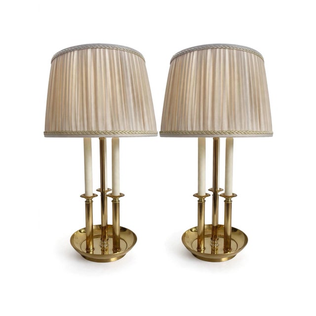 A stunning pair of vintage brass bouillotte table lamps featuring a classic 3-arm candelabra design with faux candles....