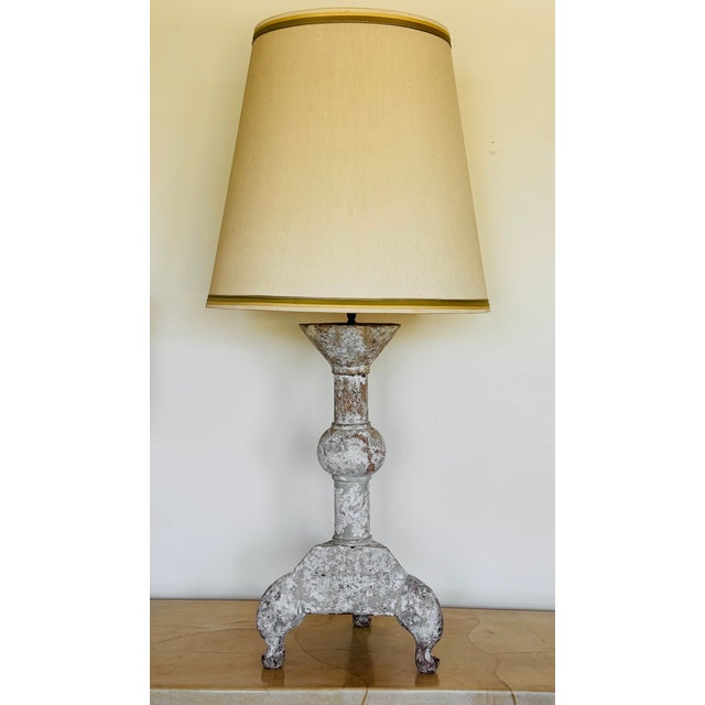 A large painted wood altar stick converted into a lamp. Decades of paint are revealed throughout the distressed surface...