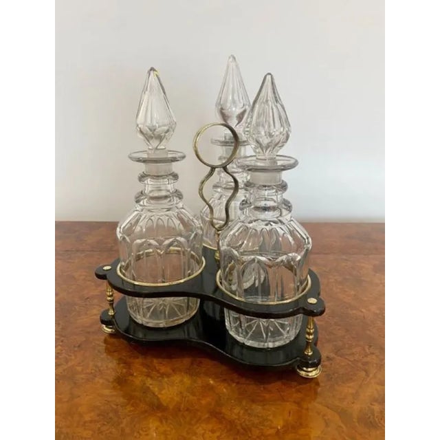 Quality decanter stand with three original cut glass decanters. Quality lacquered decanter stand with three brass columns,...