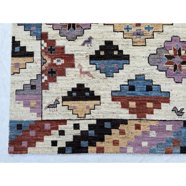 A joyful, graphic tribal area rug on a creamy ivory field, packed with stepped pixel medallions and star-centered rosettes...