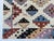 A joyful, graphic tribal area rug on a creamy ivory field, packed with stepped pixel medallions and star-centered rosettes...